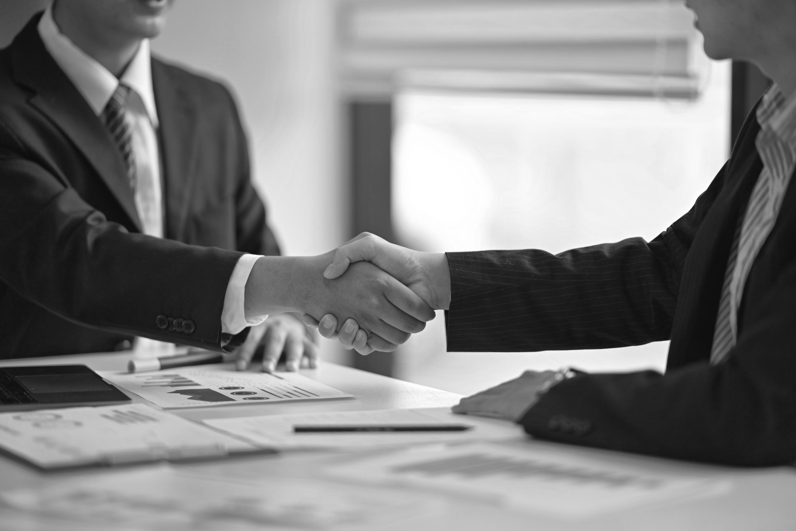 A handshake between two business people at a table